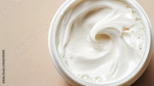 White Cream Swirl in Open Round Jar Top View Beige Background