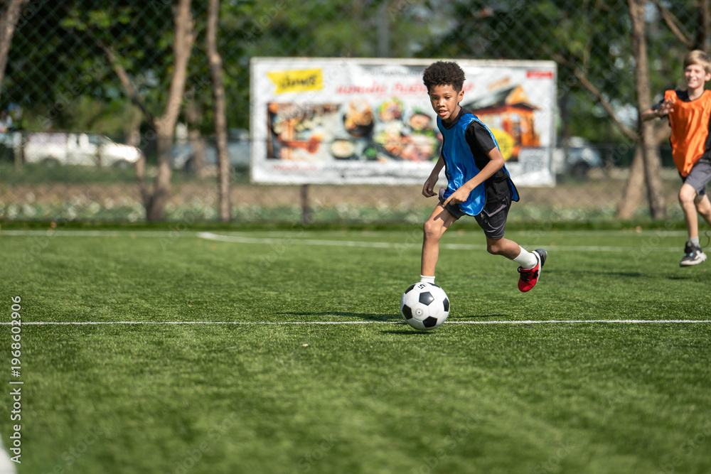 Obraz premium Group of international school kids playing soccer together on the field