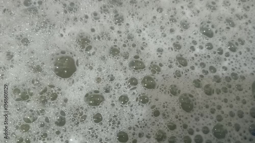 Close up of white soap bubbles foam on water surface background, Macro shot of laundry detergent foam with soap bubbles texture