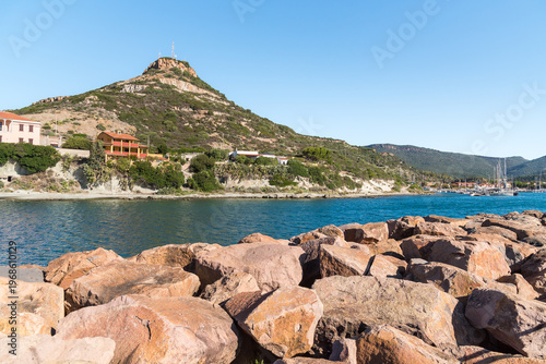 The coast of Bosa Marina, a charming seaside village located in Sardinia, Italy. Scenic Mediterranean coastline with sandy beach, colorful buildings, and clear blue sea.