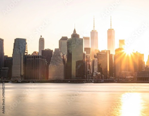 Sunset over modern city skyline with river view.