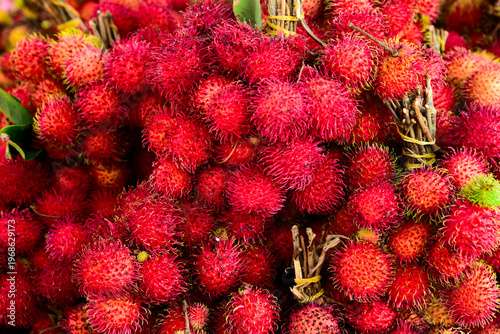 Bunch of red rambutans are piled on top of each other. The rambutans are ripe and ready to eat