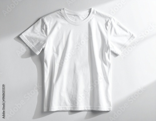 A clean, plain white t-shirt lies flat against a white surface, casting soft shadows