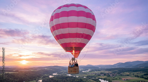 A pink hot air balloon flying over a serene landscape at sunset