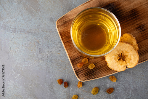 Glass of apple juice with dried apples and raisins on a wooden board