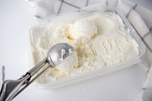 Scooping creamy vanilla ice cream from a container