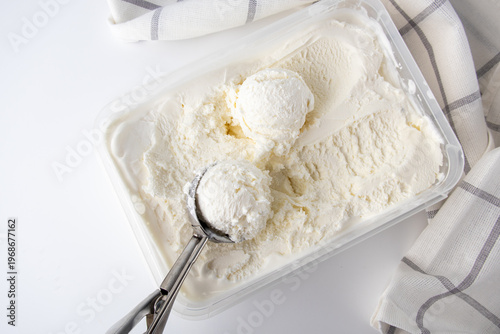 Scooping creamy vanilla ice cream from a container
