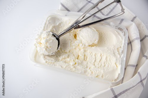 Scooping creamy vanilla ice cream from a container