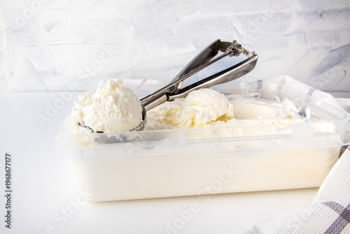 Scooping creamy vanilla ice cream from a container