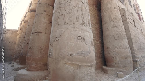 Low angle view of massive ancient stone columns with intricate hieroglyphic carvings at the historic Luxor Temple in Egypt.