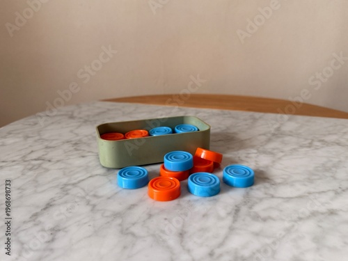 Box with vintage colorful checkers on marble table close up