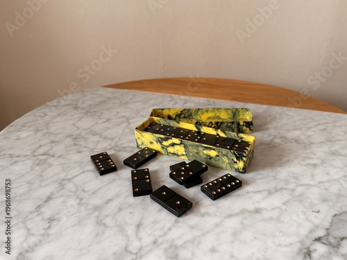 Box with vintage domino bones on marble table close up