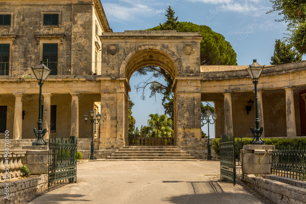 Fototapeta premium A historic, grand stone building in Corfu Old Town, flanked by stone pillars, and illuminated by several street lamps