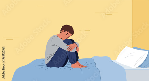 A sad young person sitting alone on a bed with knees pulled against their chest