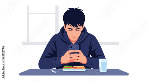 A young man sitting at a table looking down at his smartphone while eating food