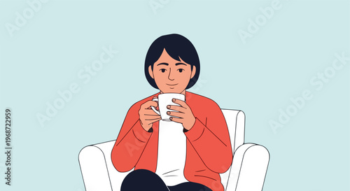 A person with short dark hair sitting in a white armchair holding a coffee mug
