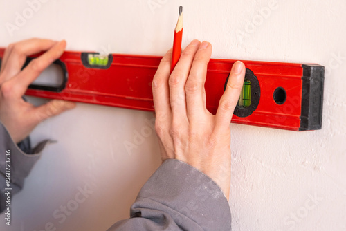 Fotografi Drawing wall marking using spirit level, accuracy in layout for renovation, positioning fixings, installation guideline, professional construction tools