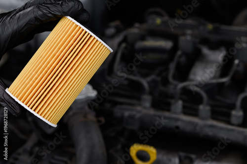 Car maintenance. Professional mechanic performs precise inspection and repair of vehicle systems while holding an oil filter. Oil and oil filter changes for diesel vehicles