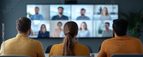 Rear view diverse team watches a large screen showing blurred video conference participants, highlighting global remote teamwork and digital collaboration., hybrid work, online meeting