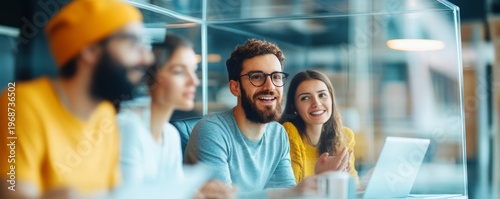 Smiling diverse team engaging in a modern office collaboration. Bearded man in glasses and woman in focus, showing successful teamwork, creative discussion and innovation by a laptop.