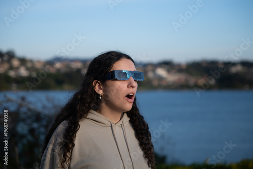 Teenage girl observing a solar eclipse with protective glasses outdoors