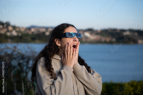 Teenage girl observing a solar eclipse with protective glasses outdoors