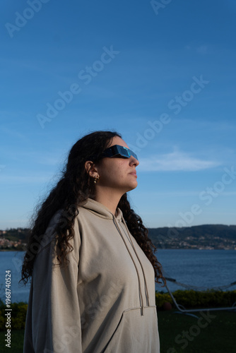 Teenage girl observing a solar eclipse with protective glasses outdoors, vertical image 