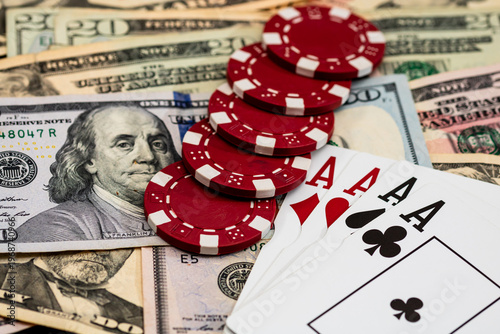 Stack of poker chips over american dollar bills and playing cards representing casino gambling