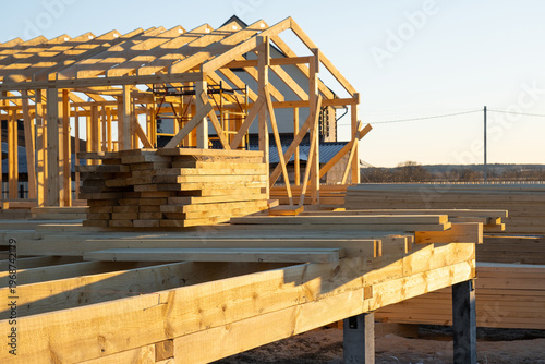 Timber beams on foundation, wood frame structure, skeleton mounting, assembly stage of construction, bracing, carpentry, modern building, exterior site, workplace.