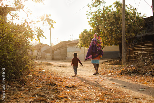 Child and father are walking together on a village path at dawn