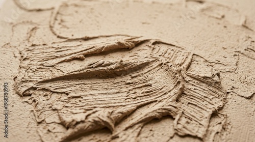 Close-up of textured clay being sculpted with visible brush strokes, creating a warm, earthy tone against a neutral background.