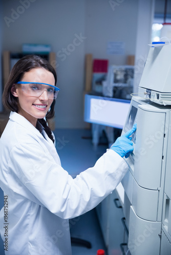 Female lab technician pressing panel to start test, generating animated charts on monitor