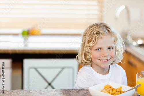 Cereal bowl sitting on kitchen counter beside glass of orange juice, sink faucet glinting