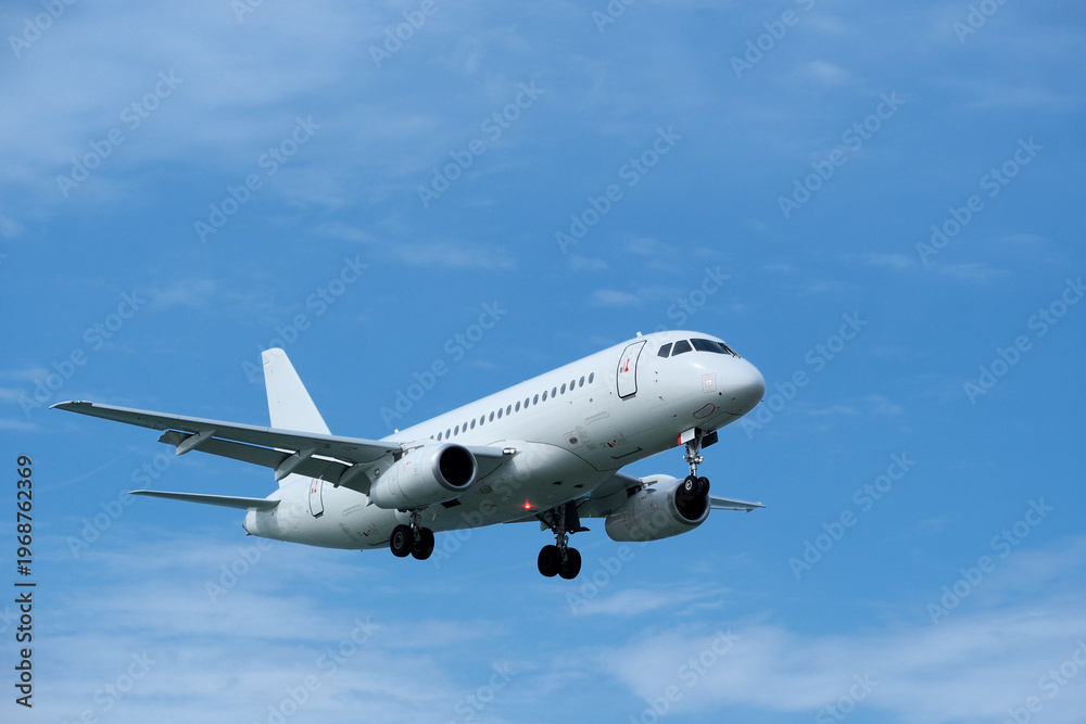 Fototapeta premium Detailed Close-up of Commercial Airplane Landing under Clear Blue Sky with Scattered Clouds.