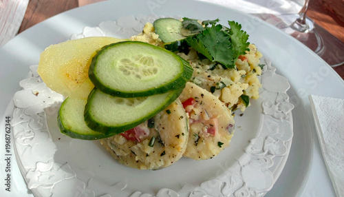 Meat tartare topped with fresh cucumber slices served with herb mashed potatoes on white plate
