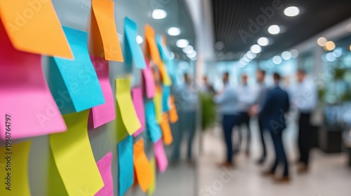 Innovation on Display: A vibrant display of colorful sticky notes punctuates an office, acting as a dynamic backdrop to a collaborative meeting.