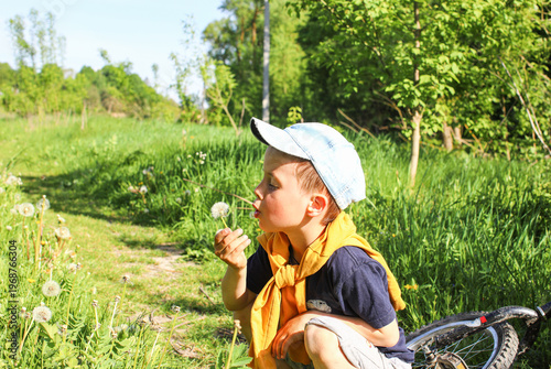 Little boy holding a bouquet of dandelion parachutes - happy child with wildflowers, spring mood, childhood and carefree nature.
