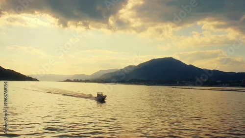 Boat Crossing Mountain Lake at Sunset Scenic Nature Landscape Travel Adventure Reflection Water Calm Evening Sky Serenity Outdoor Wilderness Cinematic View 4K Video