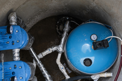 Modern water well system: hydropneumatic tank, filtration equipment, plumbing lines, pump, high-capacity water supply, domestic groundwater solution.