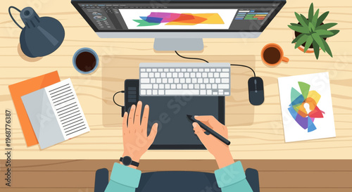 Graphic designer working on a computer with a drawing tablet, top view, creative workspace