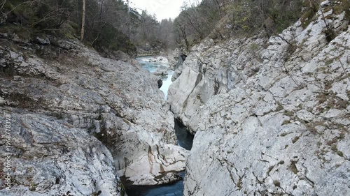 Aerial drone footage of emerald river flowing through rocky forest landscape in Soča region Slovenia