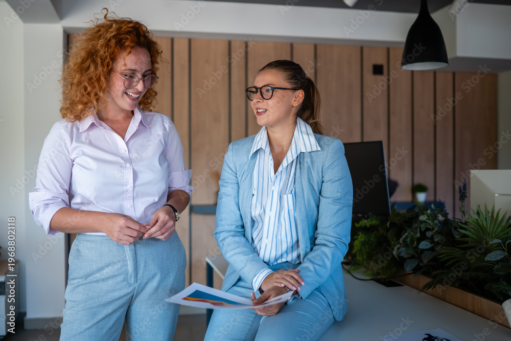 Fototapeta premium Two businesswomen collaborating and discussing work ideas in modern office