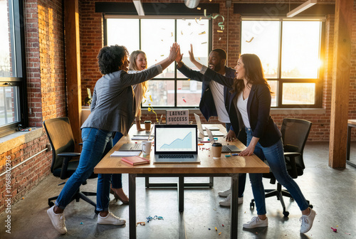 Happy diverse business team celebrating startup launch success with high fives and confetti in modern industrial office at sunset