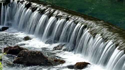 Obraz na płótnie Water rapidly cascading over a built or natural dam, forming a roaring **waterfall** or weir