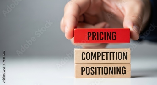Business pricing strategy concept, hand placing red wooden block on competition and positioning stack, marketing and sales management metaphor
