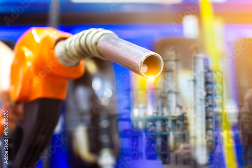 Fuel Nozzle and Refinery Industry, An orange fuel pump nozzle is shown in a double exposure with a glowing industrial oil refinery, representing petroleum and gas production.