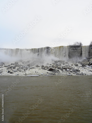 Wide winter view of waterfall with mist and rocky base