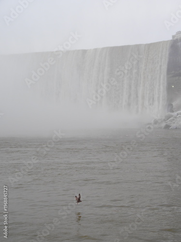 Misty waterfall edge above calm winter river