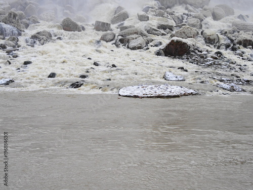 Icy riverbank with rocks and rushing winter water
