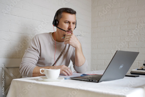 Canvastavla Serious Businessman in Headset Taking Notes During Online Seminar at Home